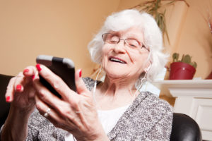 A smiling elderly woman listening to music though her ear buds.